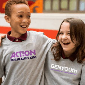 Two kids embracing while wearing t-shirts with Action for Healthy Kids logo and GENYOUth logo
